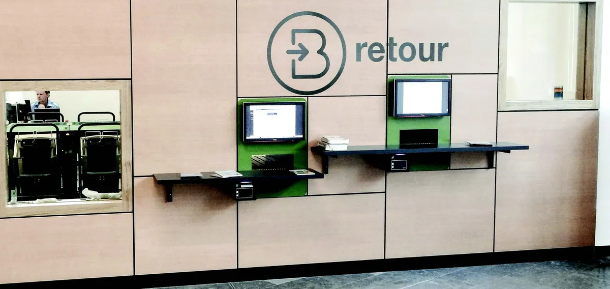 Deux automates de retour encastrés dans un mur habillé de bois, sous une signalétique « retour »