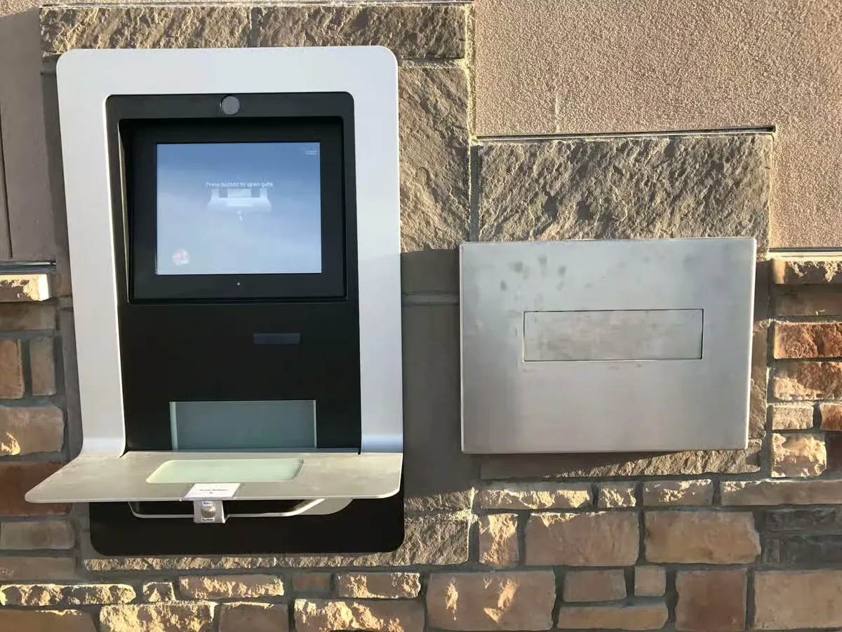 Automate de retour extérieur encastré dans un mur en pierre de teinte sable, vu de la rue